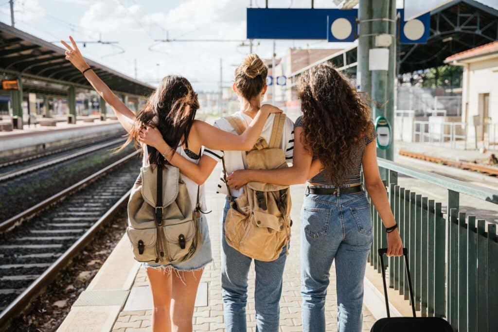 Three girls walking with backpacks at train station