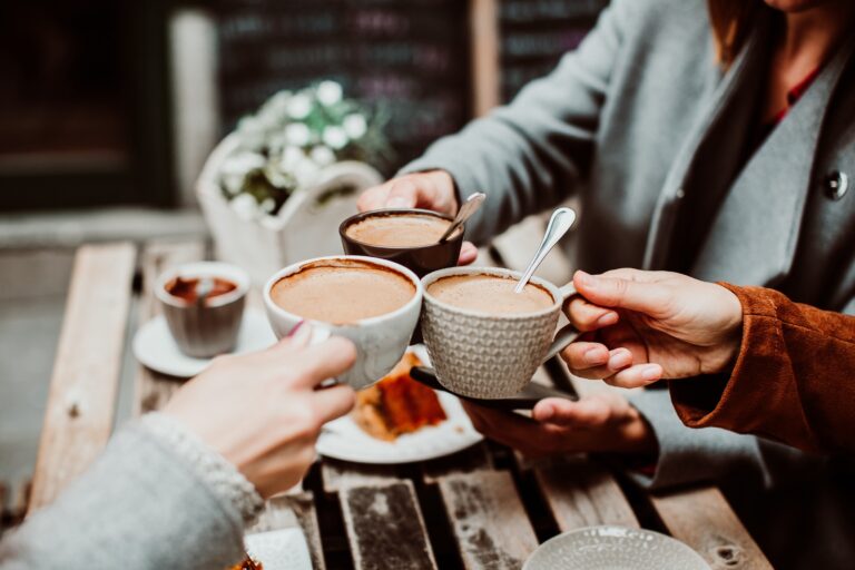 Group of young friends drinking coffee with cakes in an outdoor cafe